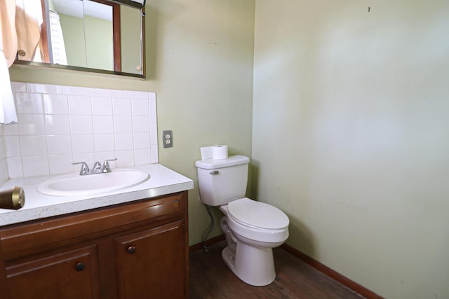 half bath with tasteful backsplash, baseboards, toilet, wood finished floors, and vanity