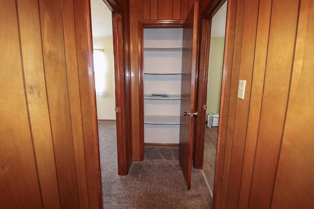 corridor with wooden walls and dark colored carpet