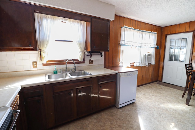 kitchen featuring light floors, light countertops, a sink, wooden walls, and a textured ceiling