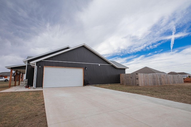 view of side of property featuring a garage, a lawn, fence, and concrete driveway