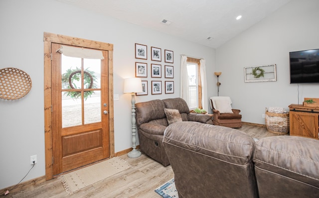 living area with light wood-style floors, baseboards, visible vents, and vaulted ceiling