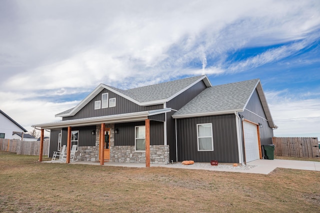 view of front of house with covered porch, fence, concrete driveway, and a front yard