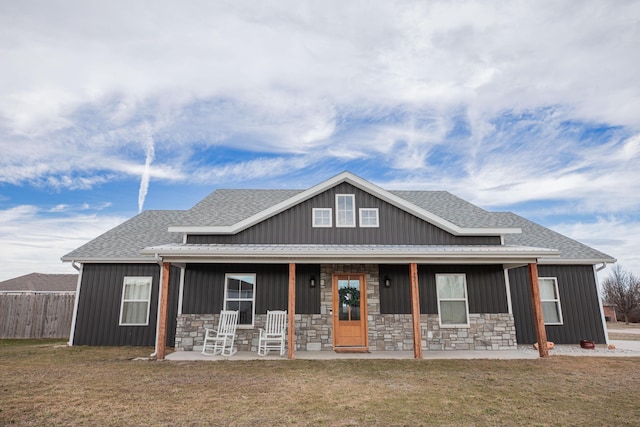 view of front of house featuring a shingled roof, a front lawn, a porch, and board and batten siding