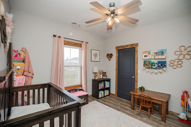 bedroom featuring wood finished floors, visible vents, and a ceiling fan