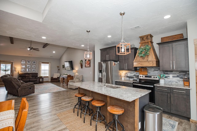 kitchen featuring stainless steel appliances, premium range hood, a sink, a kitchen breakfast bar, and backsplash