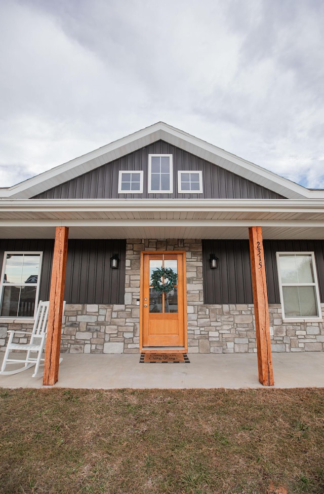 view of front of home with board and batten siding, stone siding, and a porch