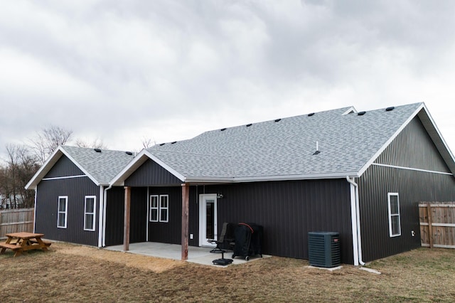 back of property with roof with shingles, a yard, central AC unit, a patio area, and fence