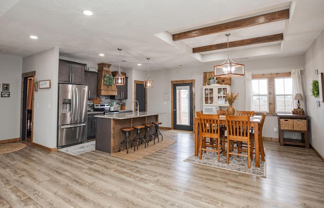 dining space with light wood finished floors, baseboards, a raised ceiling, and recessed lighting