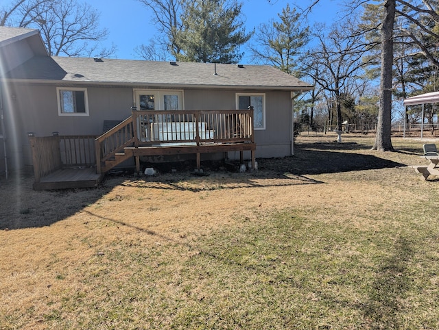 rear view of house featuring a shingled roof, a lawn, and a wooden deck