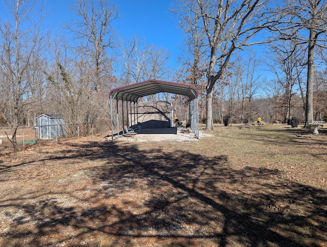 view of yard featuring dirt driveway, fence, a carport, and an outdoor structure