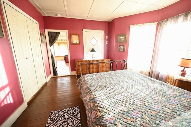 bedroom with dark wood-style floors, a closet, and baseboards