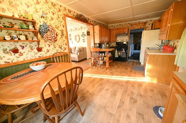 dining area with light wood-type flooring and wallpapered walls