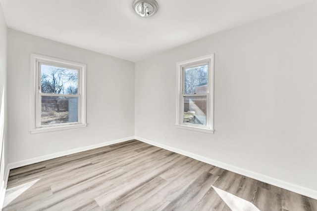 unfurnished room featuring plenty of natural light, baseboards, and wood finished floors