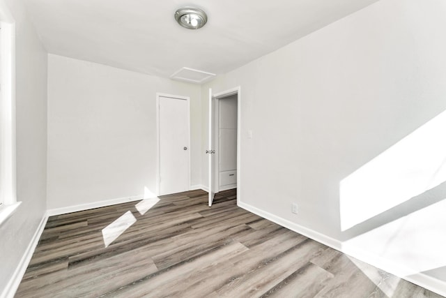 spare room featuring attic access, baseboards, and wood finished floors