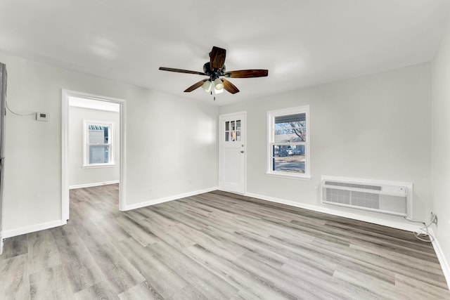 empty room featuring a healthy amount of sunlight, wood finished floors, and a wall mounted AC