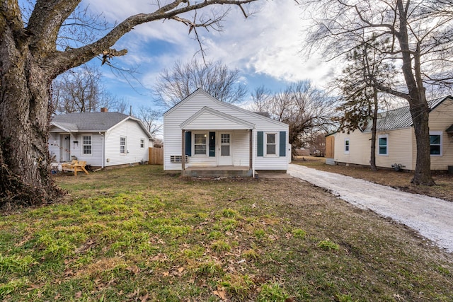 bungalow-style home with driveway, covered porch, and a front yard