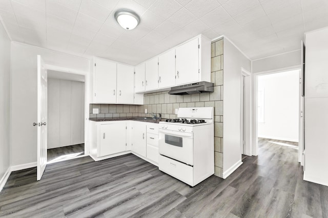 kitchen featuring under cabinet range hood, white range with gas stovetop, white cabinetry, tasteful backsplash, and dark wood finished floors