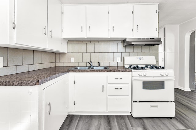 kitchen featuring arched walkways, under cabinet range hood, a sink, white cabinetry, and white gas range oven