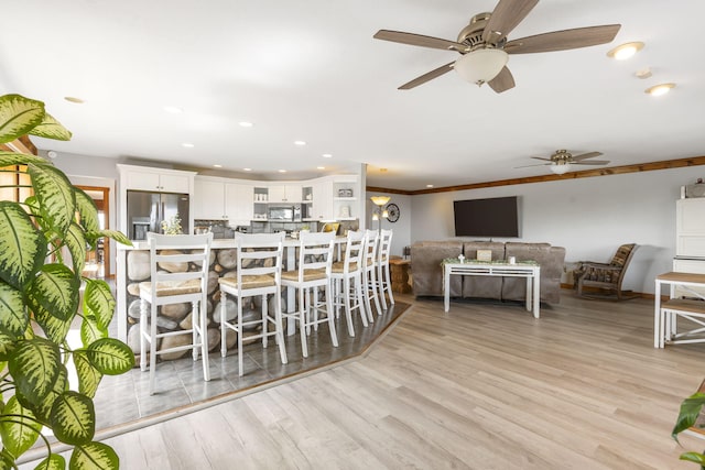 kitchen with glass insert cabinets, ornamental molding, stainless steel appliances, light wood-type flooring, and white cabinetry