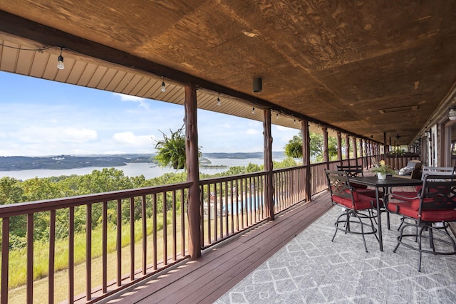 wooden terrace featuring outdoor dining space and a water view