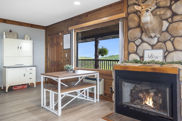 dining room featuring light wood-type flooring, a lit fireplace, and wooden walls