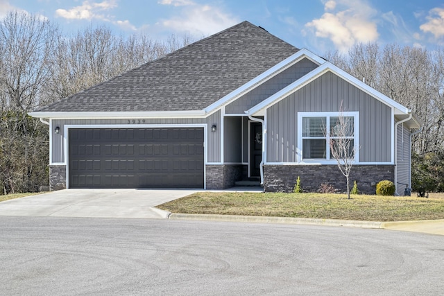 view of front of home with driveway, a shingled roof, stone siding, an attached garage, and board and batten siding