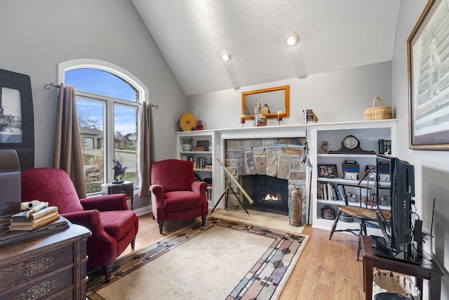 living room with a fireplace, vaulted ceiling, a textured ceiling, and hardwood / wood-style flooring