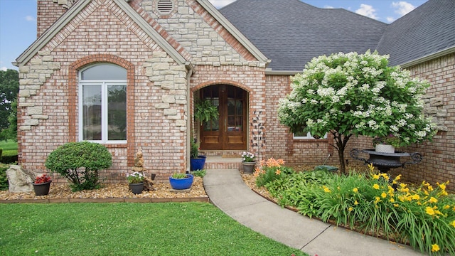 property entrance with french doors, a chimney, a shingled roof, and brick siding