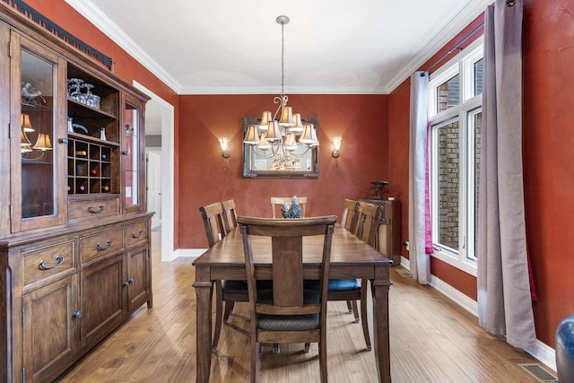 dining area with light wood finished floors, baseboards, visible vents, crown molding, and a chandelier