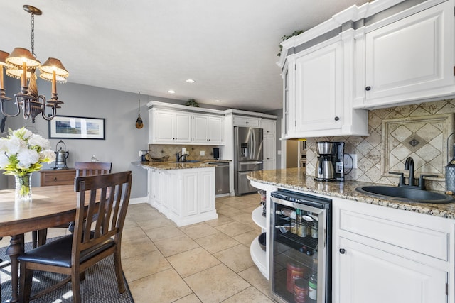 kitchen with beverage cooler, stainless steel appliances, a sink, and white cabinetry