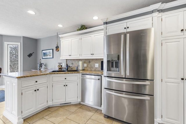 kitchen featuring stainless steel appliances, a peninsula, a sink, visible vents, and light stone countertops