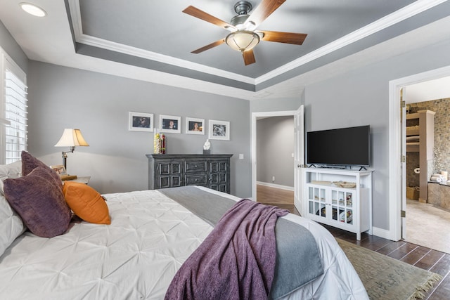 bedroom featuring baseboards, wood finished floors, a raised ceiling, and crown molding