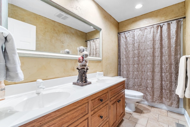 bathroom with toilet, double vanity, visible vents, and a sink