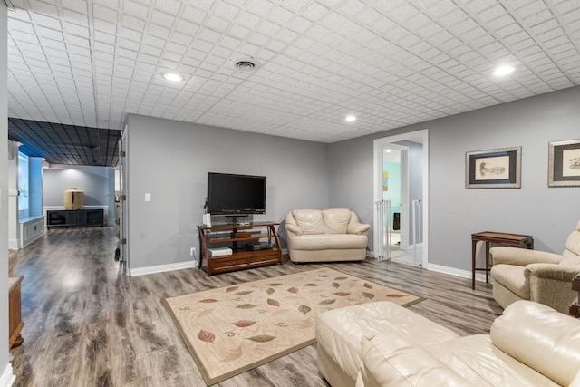 living area with recessed lighting, visible vents, baseboards, and wood finished floors