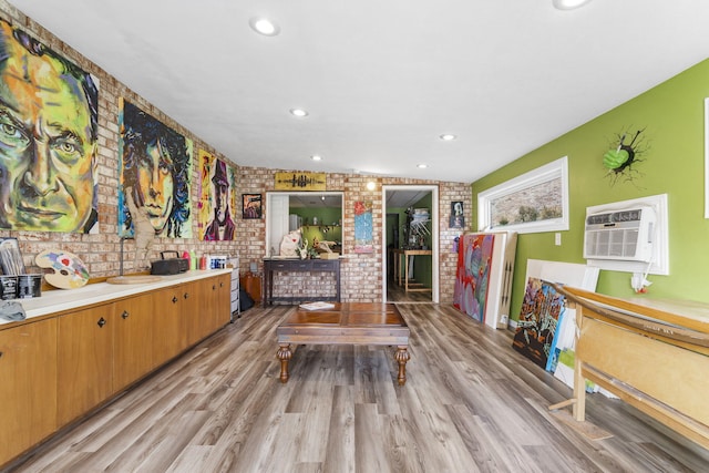 interior space with brick wall, a wall unit AC, light wood-style flooring, and recessed lighting