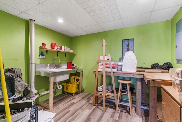 office area featuring a paneled ceiling, wood finished floors, and a workshop area