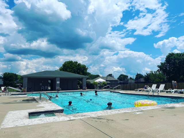 community pool with a patio and fence