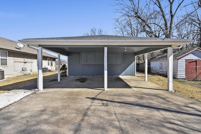 view of vehicle parking featuring an attached carport, driveway, and a storage shed