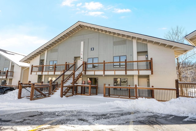 snow covered rear of property featuring a balcony and brick siding