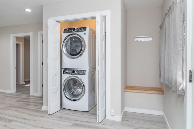 clothes washing area with recessed lighting, laundry area, stacked washer / dryer, baseboards, and light wood finished floors