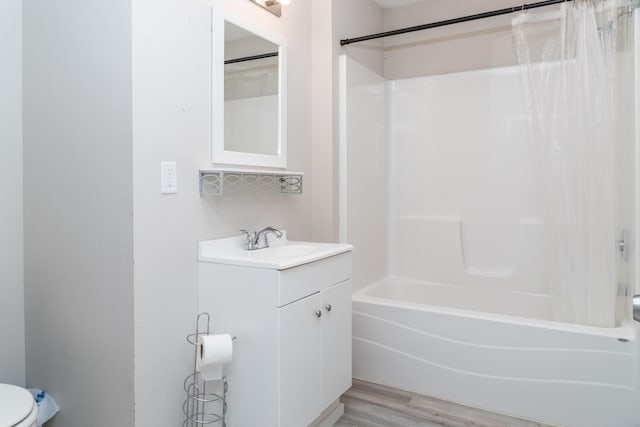 bathroom with toilet, wood finished floors, vanity, and shower / bathtub combination with curtain