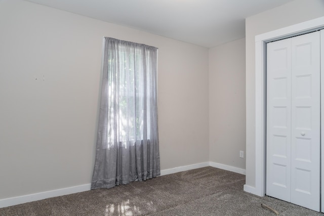 unfurnished bedroom with carpet floors, a closet, multiple windows, and baseboards