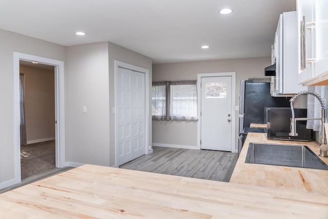 kitchen featuring extractor fan, recessed lighting, wood finished floors, white cabinetry, and baseboards