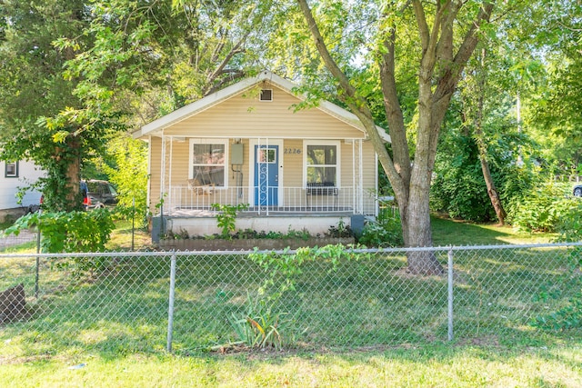 view of front of home with covered porch, a fenced front yard, and a front yard