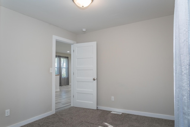 unfurnished room featuring visible vents, baseboards, and carpet flooring