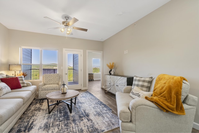 living area featuring a healthy amount of sunlight, baseboards, a ceiling fan, and wood finished floors