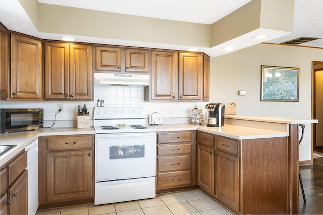 kitchen with a peninsula, white appliances, backsplash, and under cabinet range hood