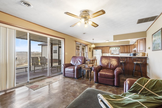 living room with finished concrete flooring, ceiling fan, and visible vents