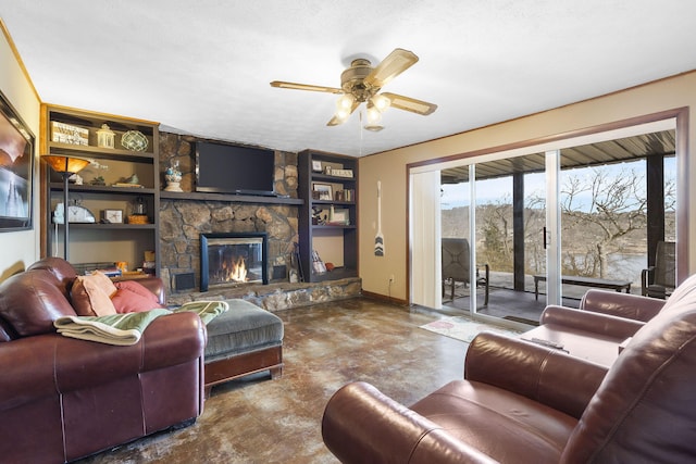 living room featuring baseboards, a ceiling fan, concrete flooring, a stone fireplace, and built in shelves