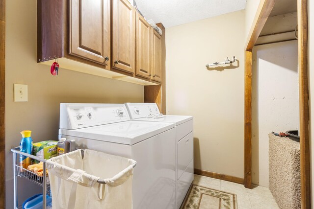 laundry area featuring cabinet space, light tile patterned floors, baseboards, a textured ceiling, and separate washer and dryer